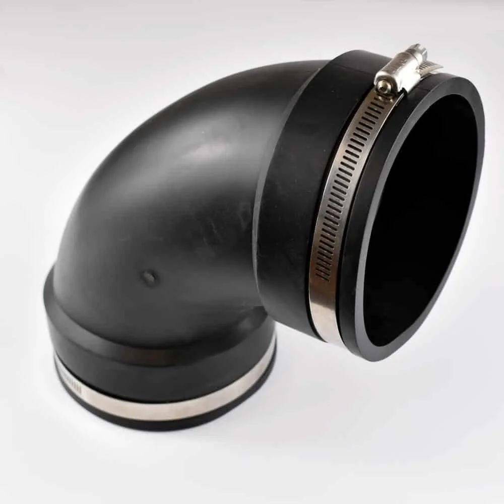 Ein schwarzes Gummikrümmerrohr mit Metallschellen an beiden Enden, das für Sanitär- oder Lüftungsinstallationen verwendet wird, ruht auf weißem Hintergrund.