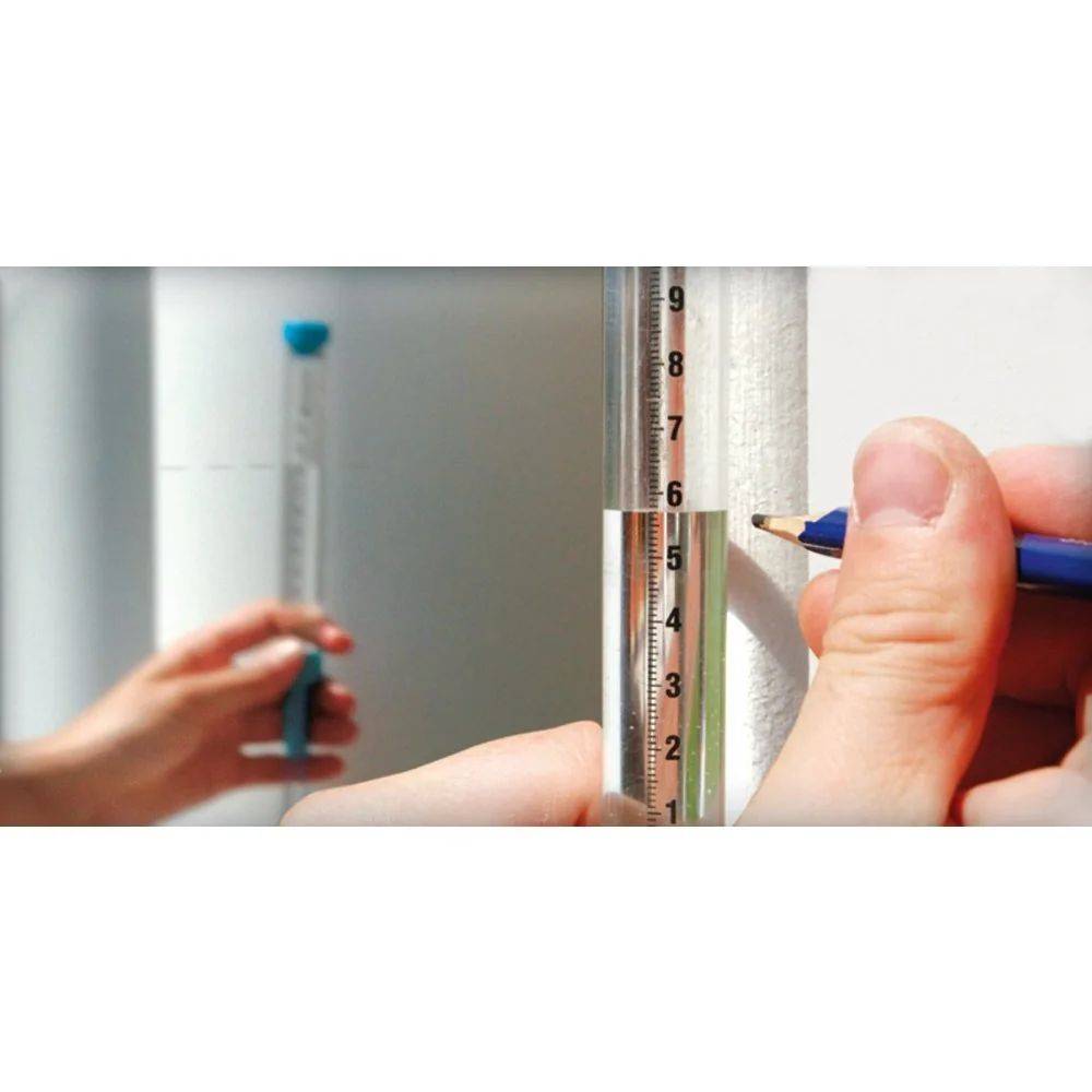 Nahaufnahme einer Hand, die mit einem Bleistift eine Messung an einer Wand neben einem vertikalen Messwerkzeug markiert, das 7 Zoll anzeigt.