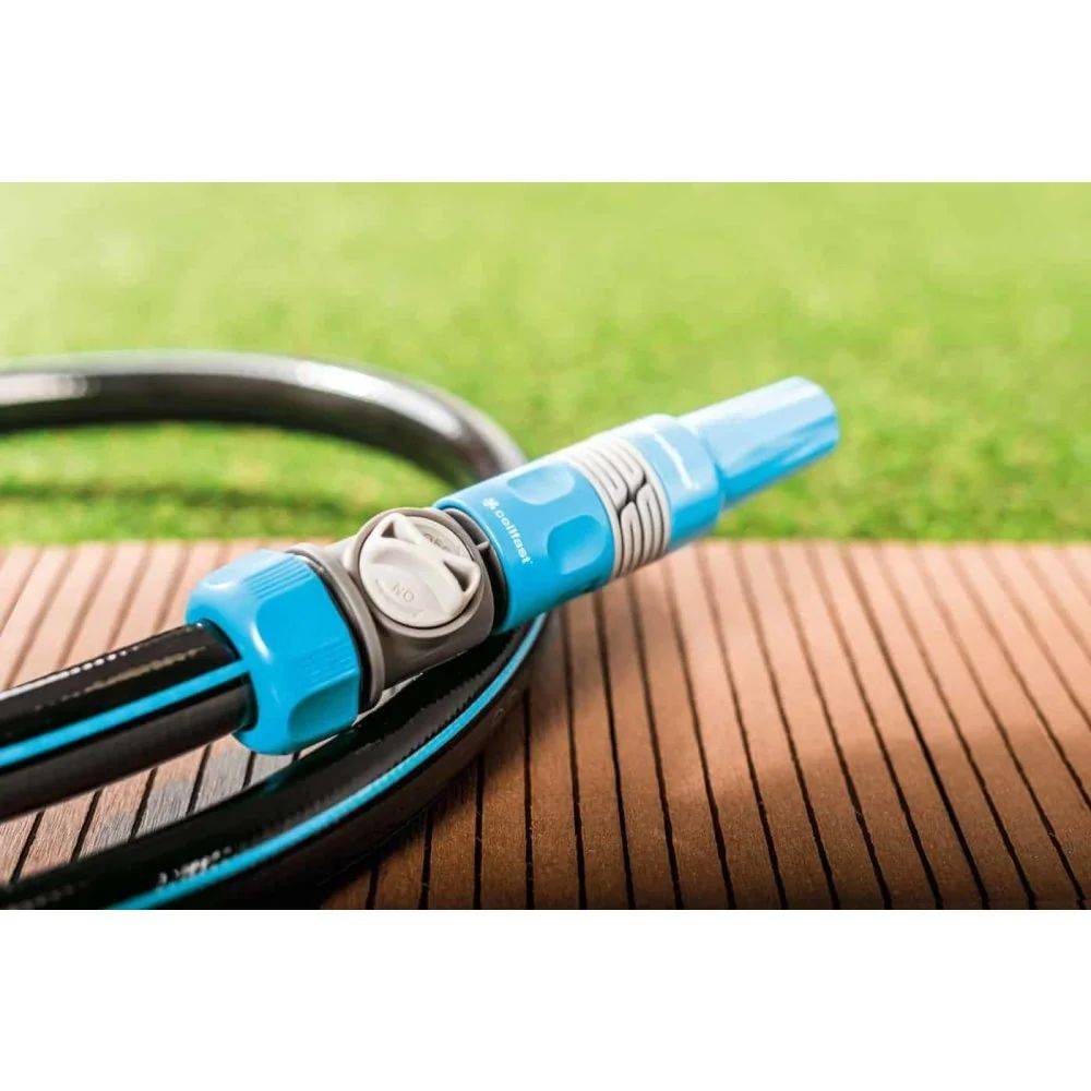 Ein blauer Gartenschlauch-Anschluss mit Ventil, auf einer Holzterrasse platziert, vor Rasen.