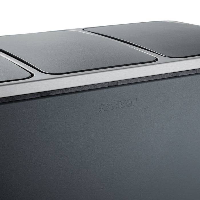 Eine schlanke schwarze Oberfläche mit einer Teilansicht eines Deckels, auf dessen Seite der Markenname 'Karat' geprägt ist.