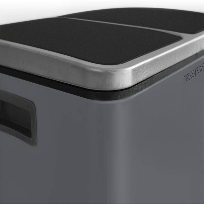 Eine Nahaufnahme eines modernen Edelstahl-Mülleimers mit schwarzem Deckel und sichtbarem Pedal.