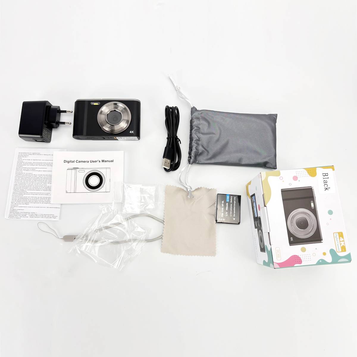 Digitalkamera mit Zubehör einschließlich USB-Kabel, Batterie, Ladegerät, Bedienungsanleitung und Tasche neben der Verpackungsbox auf weißem Hintergrund.