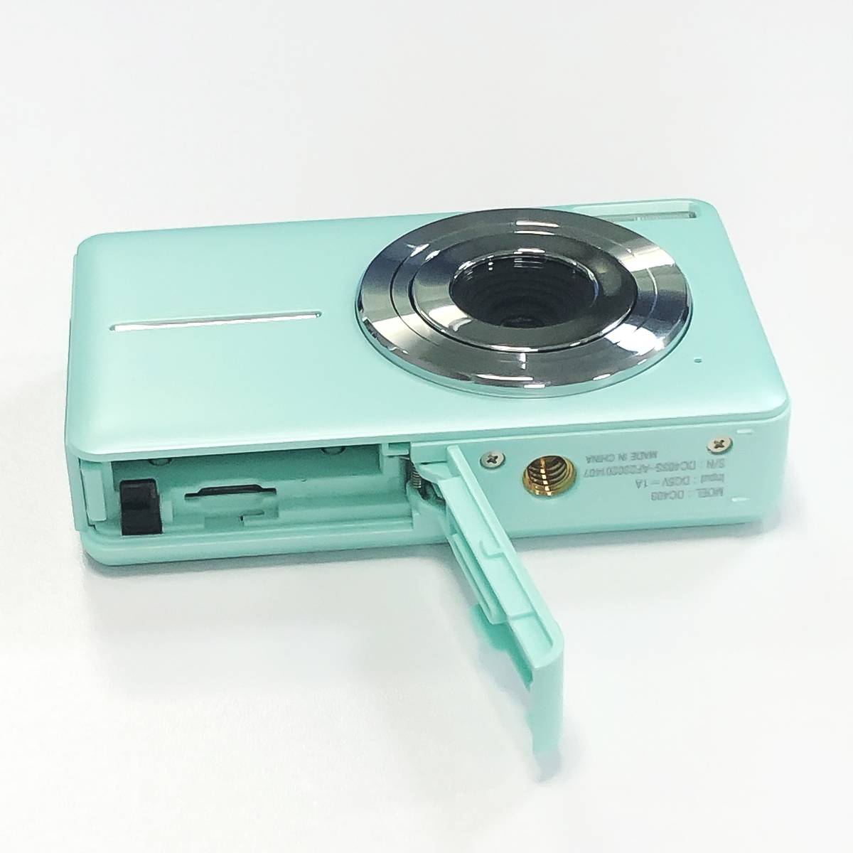 Eine hellblaue Kamera mit geöffnetem Speicherkartensteckplatz, der zeigt, wo eine Speicherkarte eingeführt ist.