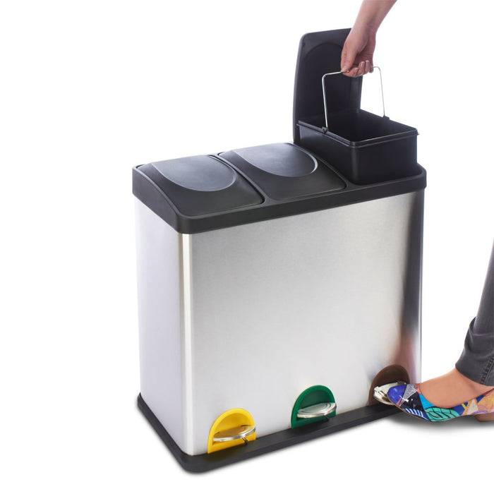 Ein Fuß drückt auf ein Pedal eines Edelstahl-Recyclingbehälters mit separaten Fächern für verschiedene Abfalltypen, gekennzeichnet mit unterschiedlichen Farben.