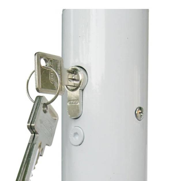 Ein Satz von Schlüsseln, die in ein Schloss an einem vertikalen weißen Pfosten eingeführt werden, was Sicherheit oder Zugriffskontrolle anzeigt.