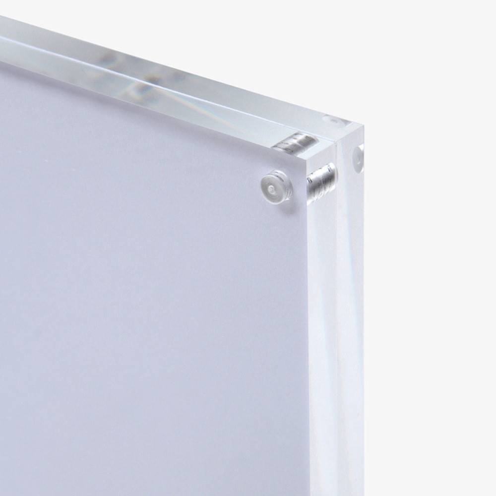 Nahaufnahme eines klaren, dicken Acrylblatts mit polierten Kanten und sichtbaren Schrauben an den Ecken.