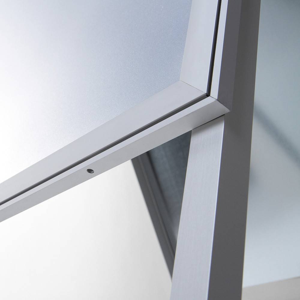 Eine Nahaufnahme einer grauen Metallecke eines modernen Schreibtischs, die das schlichte, minimalistische Design mit weicher Beleuchtung zur Geltung bringt, die die Kanten hervorhebt.
