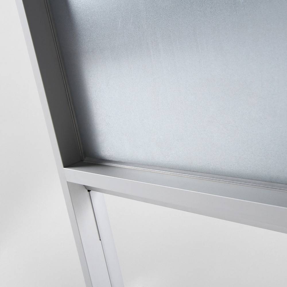 Eine Nahaufnahme einer Whiteboard-Oberfläche auf einem grauen Metallständer, die eine Eckendetail mit glatter, reflektierender Oberfläche zeigt.
