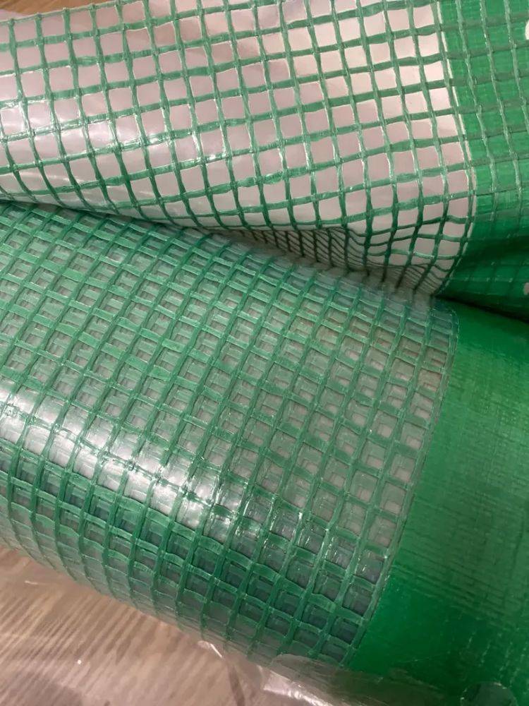 Nahaufnahme eines grünen Gittermusters auf einer Kunststoffoberfläche, möglicherweise eine Plane oder ein Tuch, die Details in Textur und Materialqualität zeigt.