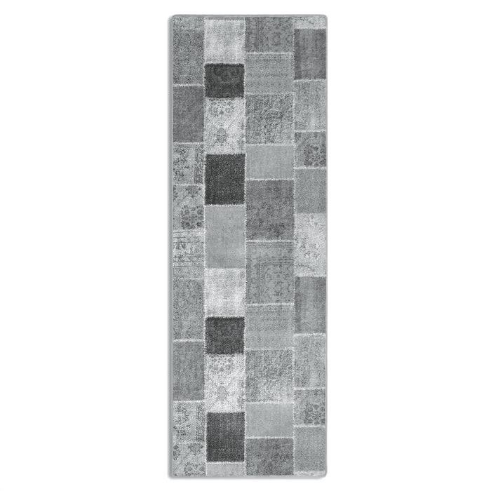 Ein langer, rechteckiger Teppich mit einem Patchwork-Design aus verschiedenen Grau- und Schwarztönen in Quadraten, die in einem vertikalen Muster angeordnet sind.