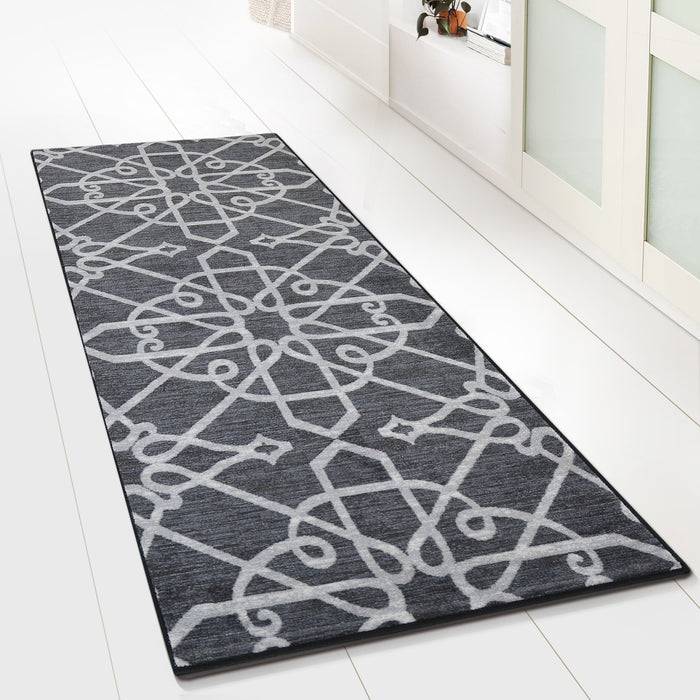 Ein moderner, geometrisch gemusterter grau-weißer Teppich auf einem hellefarbigen Boden, der sich vor einem Schiebetor-Kleiderschrank erstreckt.