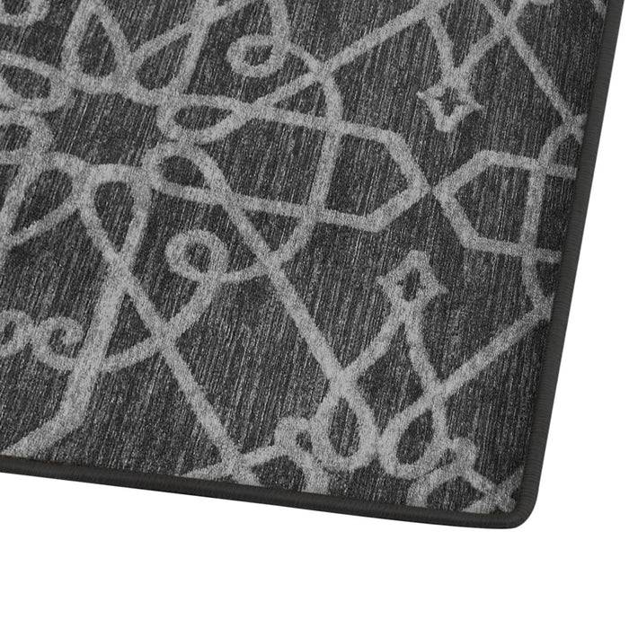 Eine Nahaufnahme eines strukturierten grauen Teppichs mit aufwendigen, verflochtenen hellgrauen geometrischen und Sternenmustern, mit schwarzem Rand.