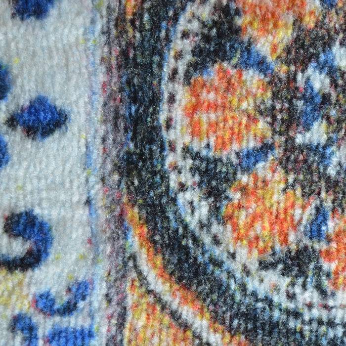 Nahaufnahme eines bunten, gemusterten Teppichs mit aufwendigen geometrischen und floralen Mustern in Blau-, Orange- und Weißtönen.