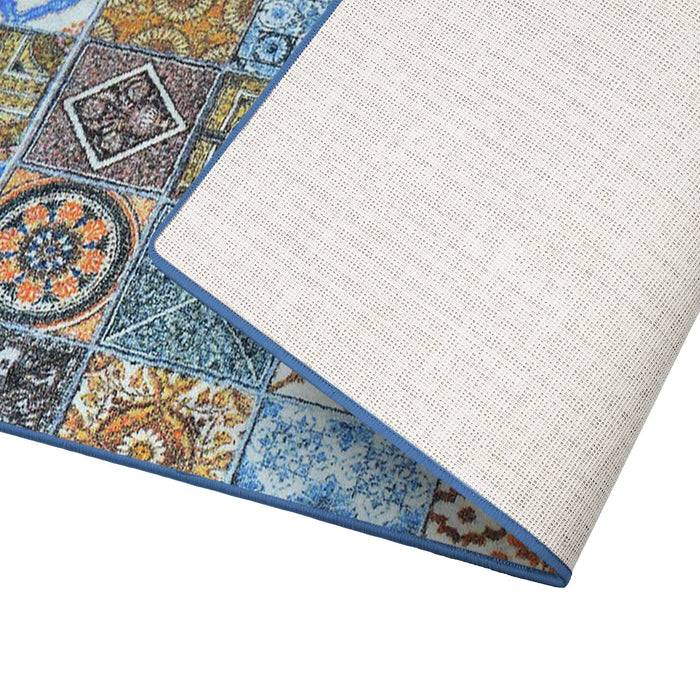 Ein gefalteter Teppich mit farbenfrohen geometrischen und floralen Fliesenmustern auf der Oberseite, mit einer einfarbig weißen Unterseite, vor weißem Hintergrund.