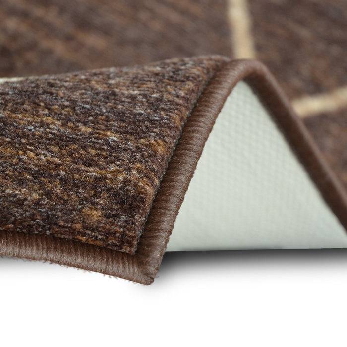 Nahaufnahme einer gefalteten Ecke eines braunen Teppichs, die strukturierte Fasern oben und eine rutschfeste weiße Unterseite darunter zeigt.
