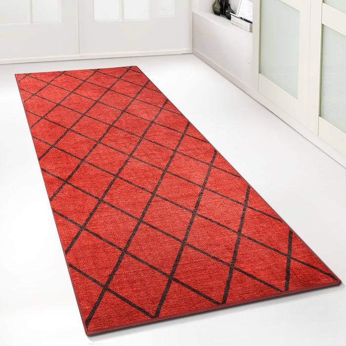Ein langer roter Teppich mit einem schwarzen Diamantmuster liegt auf einem weißen Boden und führt zu geschlossenen Doppeltüren mit Milchglaspaneelen.
