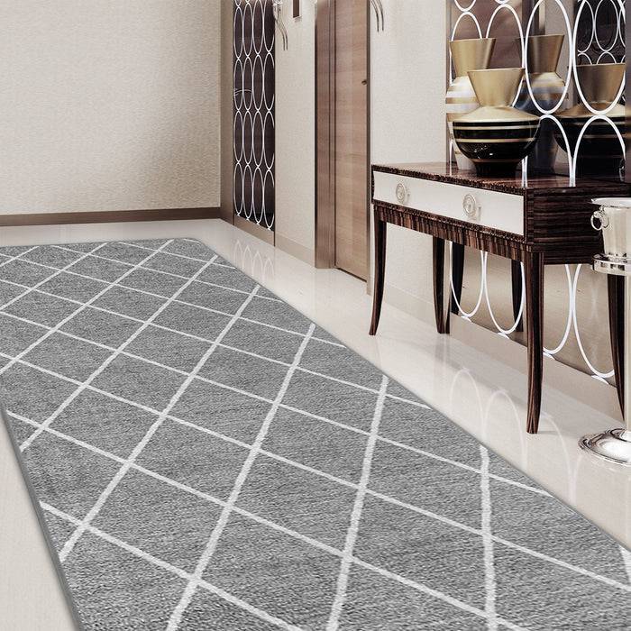 Ein Flur mit einem grau gemusterten geometrischen Teppich auf einem glänzenden Boden, einem dekorativen Konsolentisch mit Schüsseln und getäfelten Wänden mit Spiegeln.