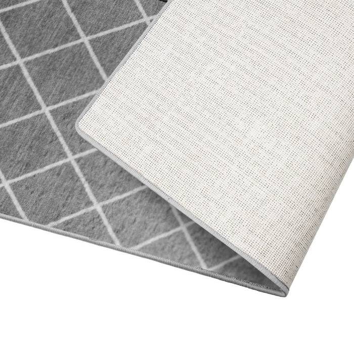 Eine Ecke eines grauen Teppichs mit weißem Rastermuster, umgeklappt, um die weiße Unterseite zu zeigen.