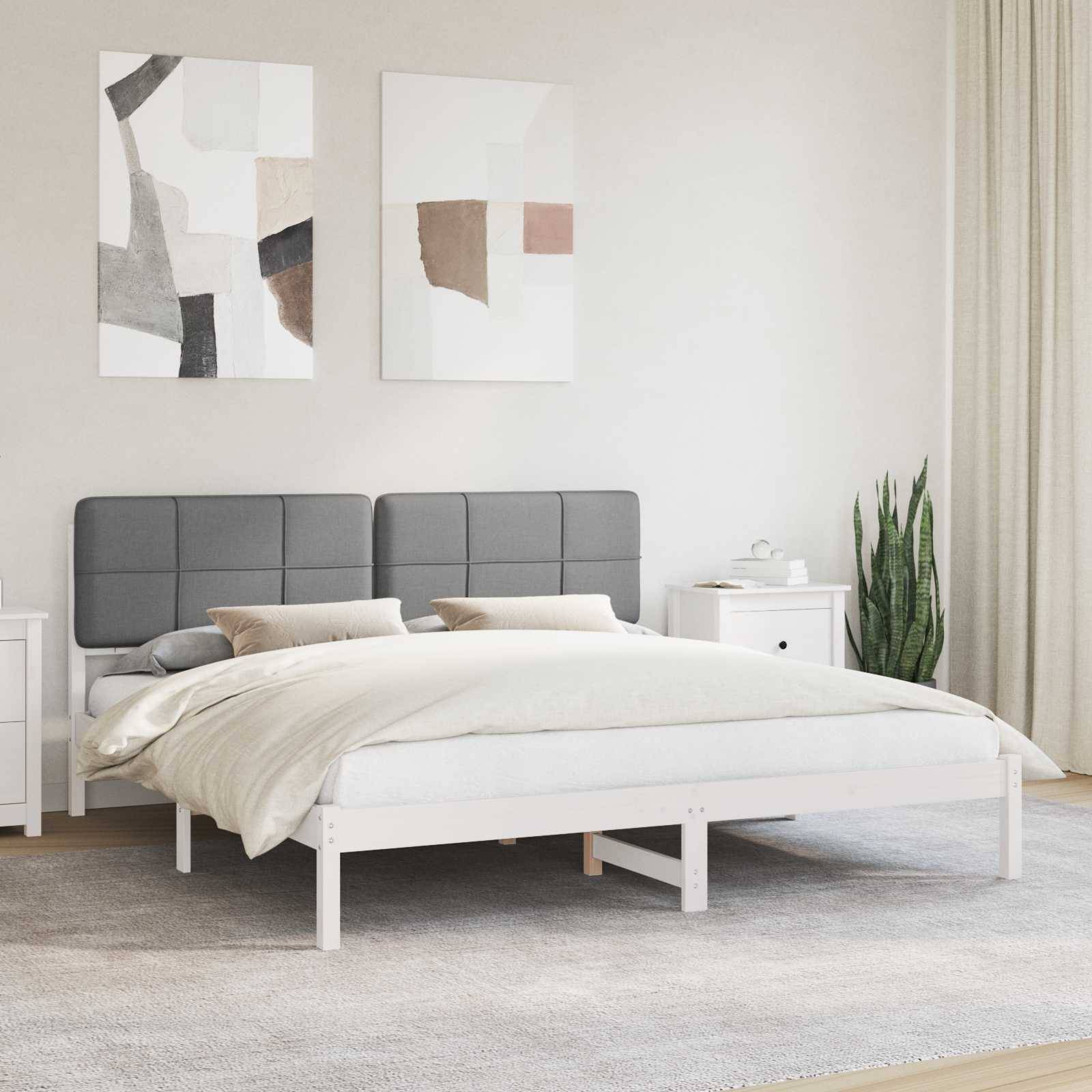 Ein modernes Schlafzimmer mit einem grau gepolsterten Bett, beigefarbener Bettwäsche und zwei abstrakten Gemälden an der Wand. Ein Nachttisch hält Dekoration und eine Pflanze.