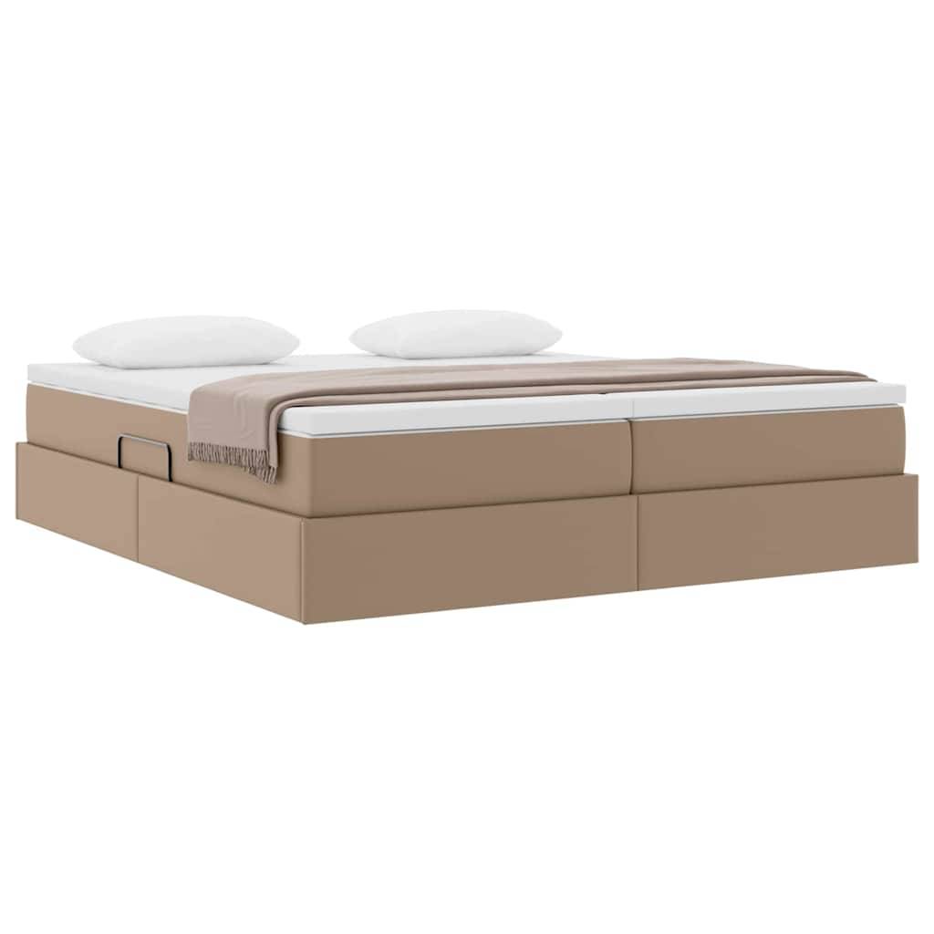 Ein beiges Boxspringbett mit einer weißen Matratze und zwei Kissen, bedeckt mit einer braunen Decke, von der Seite betrachtet.