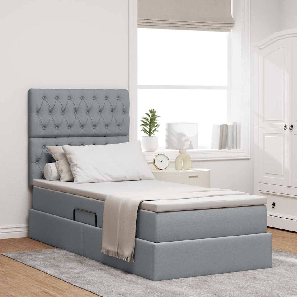Ein modernes Schlafzimmer mit einem hellgrauen gepolsterten Bett und einem gepolsterten Kopfteil. Ein kleiner Schrank und Pflanzen befinden sich in der Nähe des Fensters und bereichern die Einrichtung.