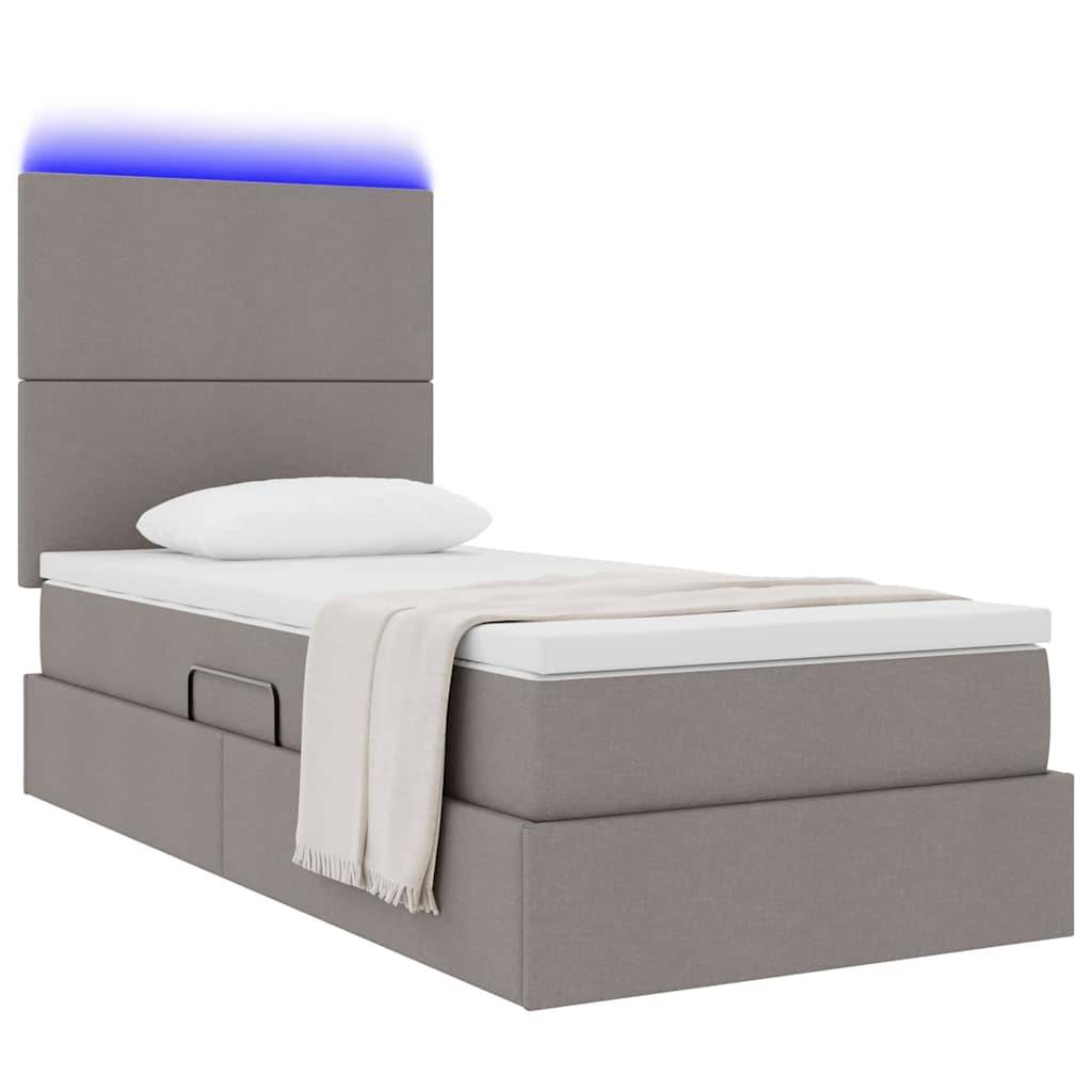Einzelnes graues Bett mit Kopfteil, weißes Kissen und beige Decke. Blaues LED-Licht über dem Kopfteil, mit Schubladenspeicher darunter.