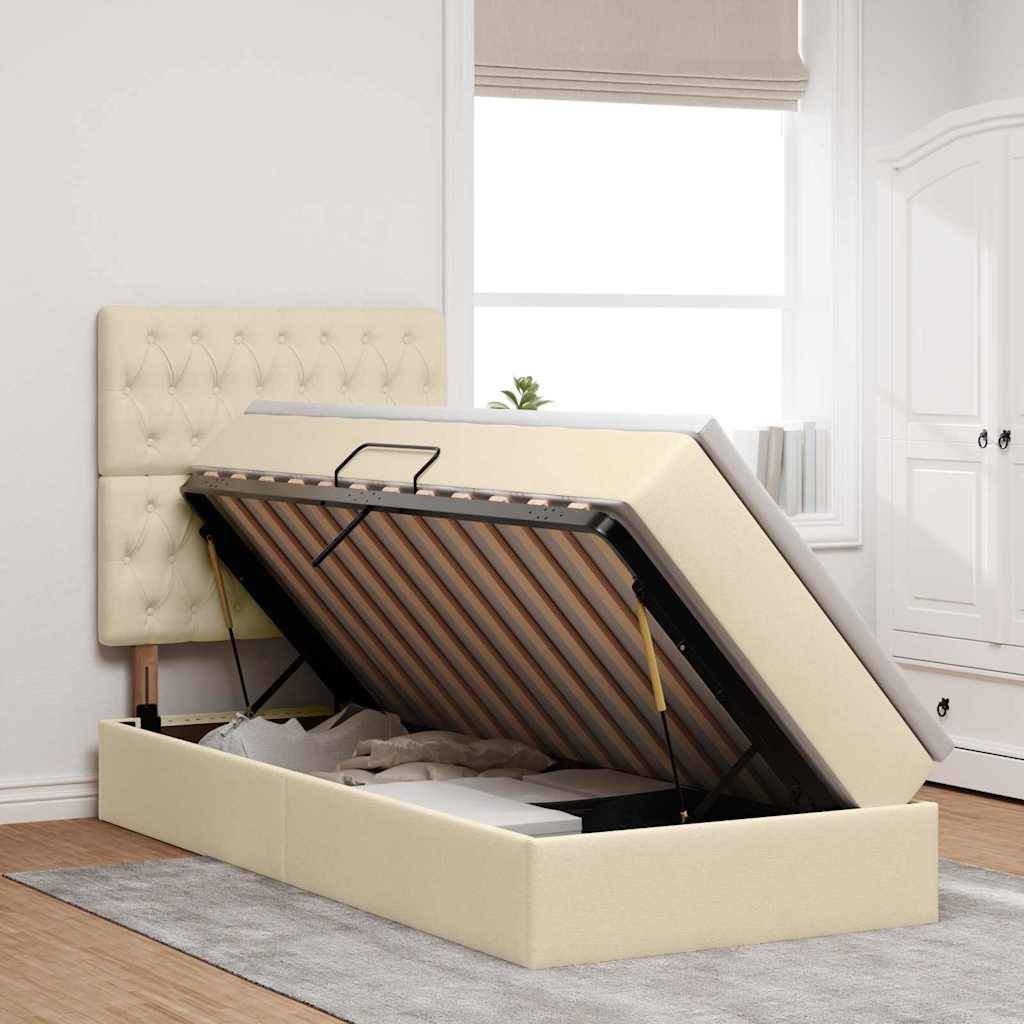 Ein beiges Ottomanenbett mit erhöhter Matratze, die Stauraum darunter zeigt, in einem hellen Schlafzimmer mit weißen Wänden und Möbeln platziert.
