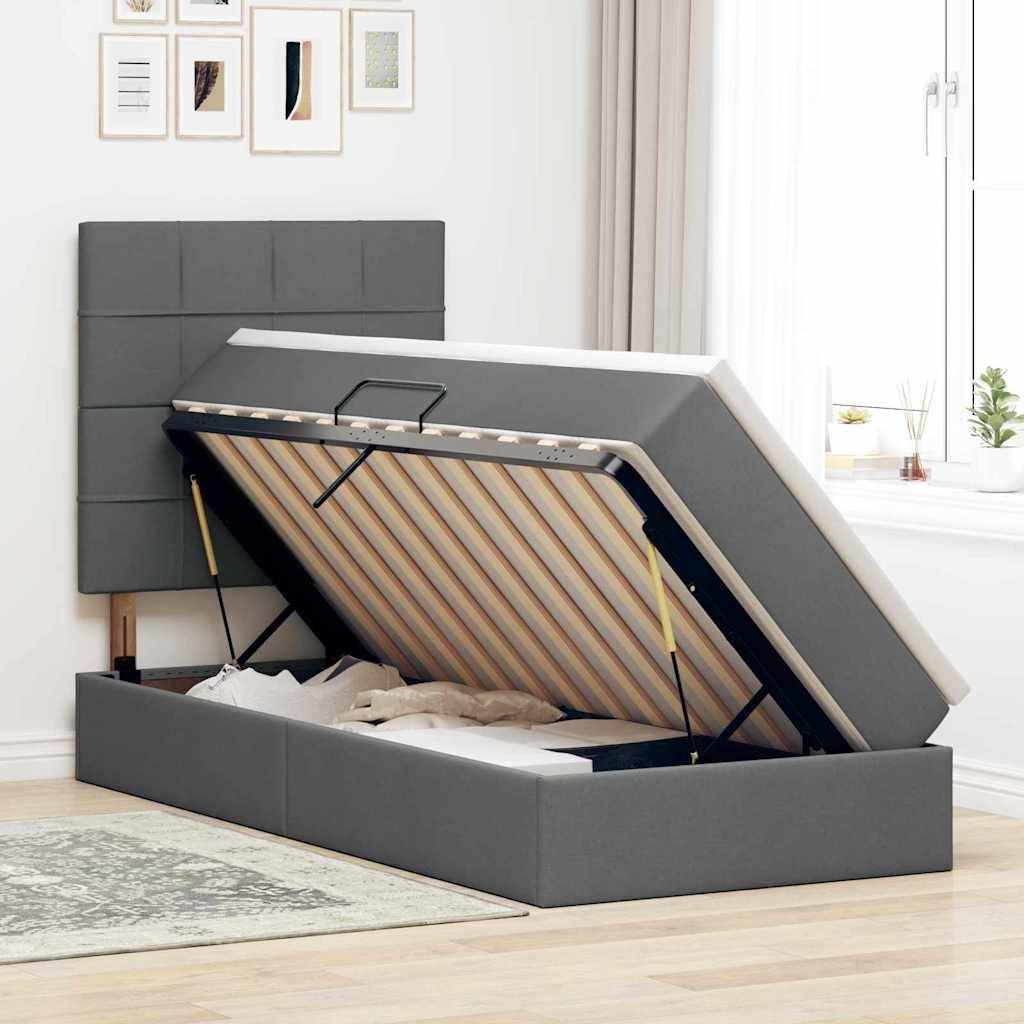Ein modernes Schlafzimmer mit einem grau gepolsterten Bett, ausgestattet mit Stauraum unter dem Bett mit einer ausklappbaren Matratze. Minimalistische Kunstwerke und ein Fenster im Hintergrund.