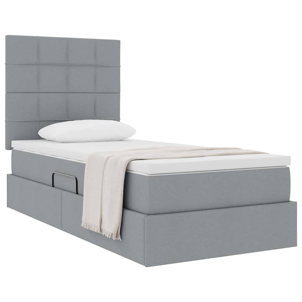 Ein graugepolstertes Bett mit gestepptem Kopfteil, ausgestattet mit einem einzelnen Kissen und einer beige farbenen Decke, die ordentlich auf der Matratze ausgebreitet ist.