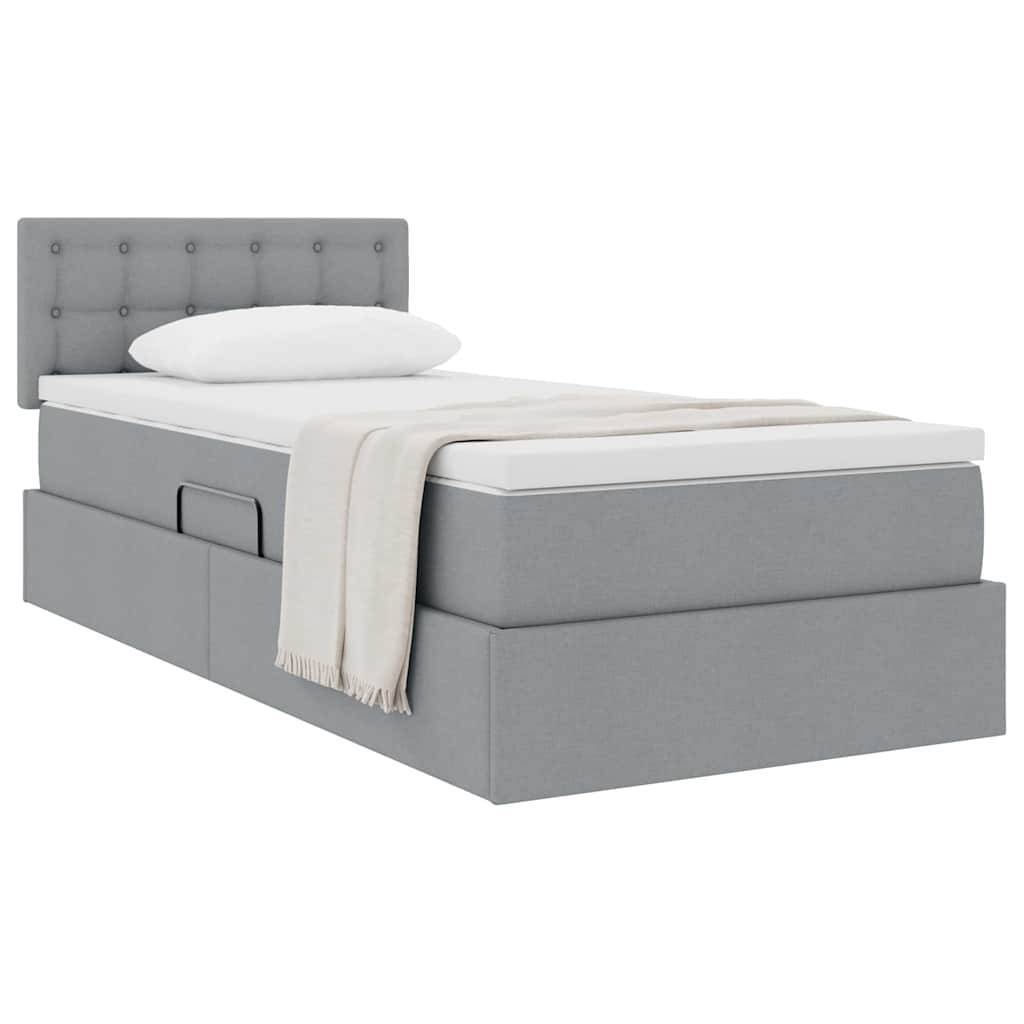 Ein grau gepolstertes Einzelbett mit gestepptem Kopfteil, ausgestattet mit einem weißen Kissen und einer beigen Wurfdecke. Das Bett verfügt über Schubladen zur Aufbewahrung.