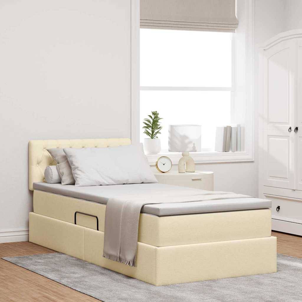 Ein beige gepolstertes Bett mit Lagerschubladen, weiße Bettwäsche und Kissen befindet sich in einem hellen Raum mit Holzböden, Teppich und einem Nachttisch.