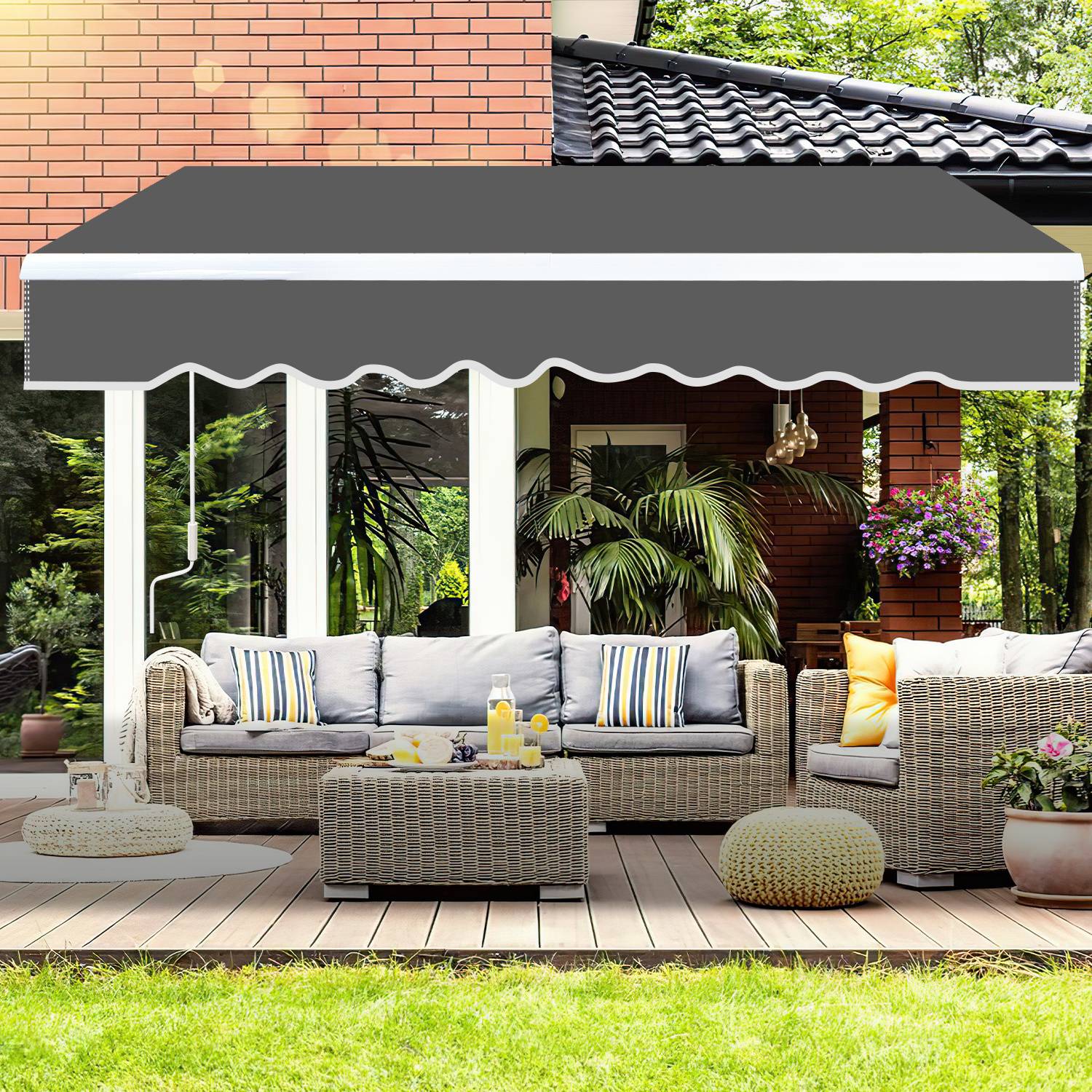 Außenterrasse mit einem Rattansofa-Set, farbenfrohen Kissen und einem kleinen Tisch mit Getränken unter einer großen schwarzen Markise, die an einem Haus befestigt ist.