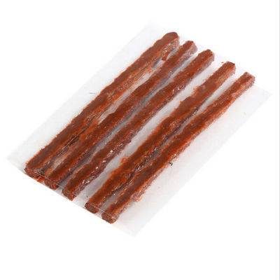Fünf dünne Streifen aus Trockenfleisch sind ordentlich auf einer weißen Oberfläche angeordnet und deuten darauf hin, dass sie möglicherweise ein Snack oder eine Zutat sind.