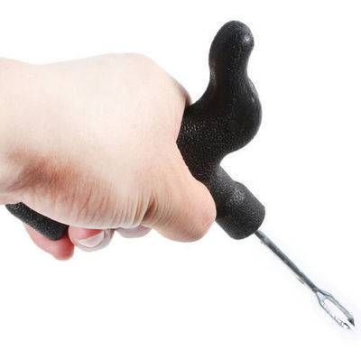 Eine Hand hält einen schwarzen ergonomischen Gartenunkrautstecher mit gebogenem Griff und Metallspitze, der für das einfache Entfernen von Unkraut entwickelt wurde.