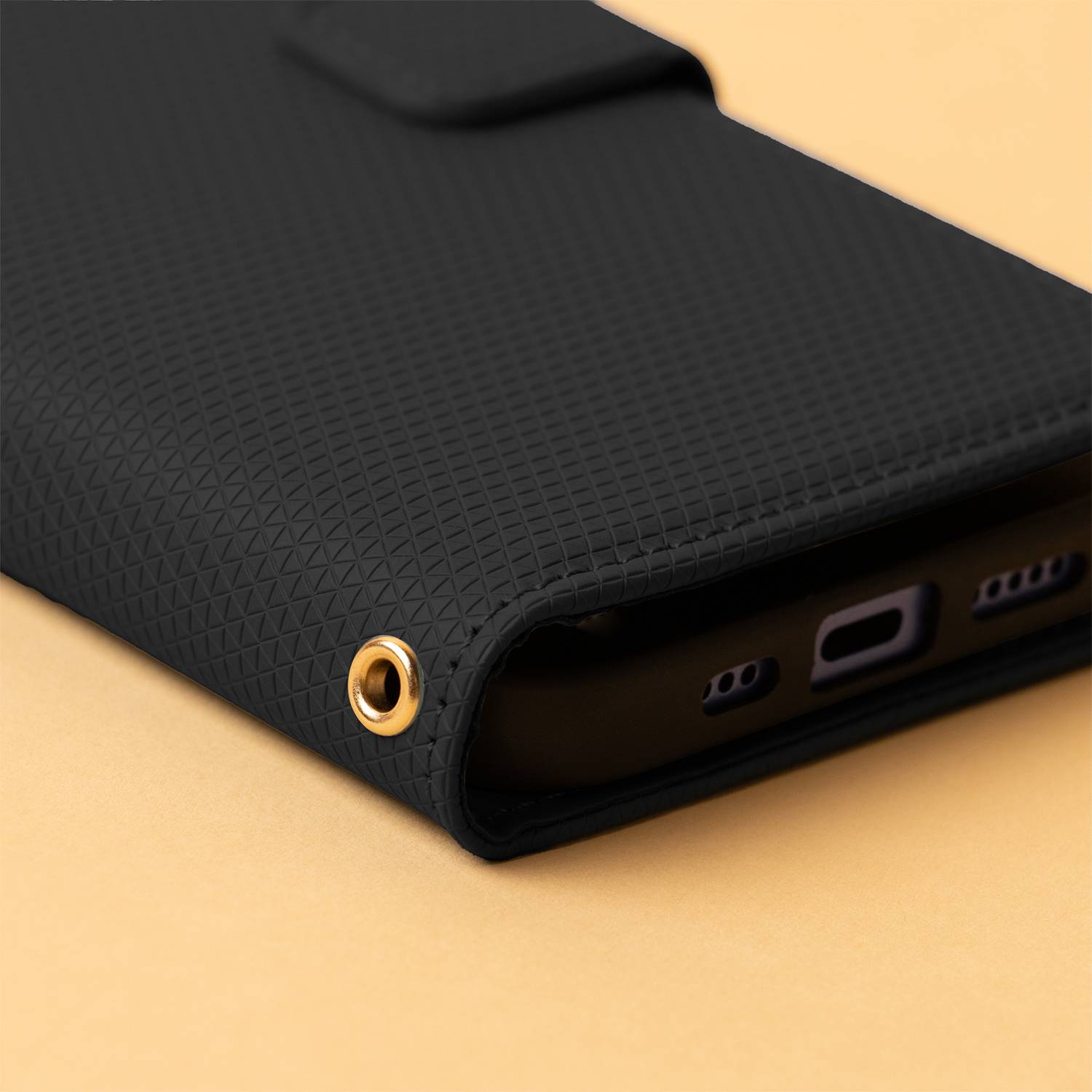 Ein rosa strukturiertes Telefongeldbörsen-Etui mit sichtbarem Ladeanschluss-Loch ruht auf einem helloran­gefarbenem Hintergrund.