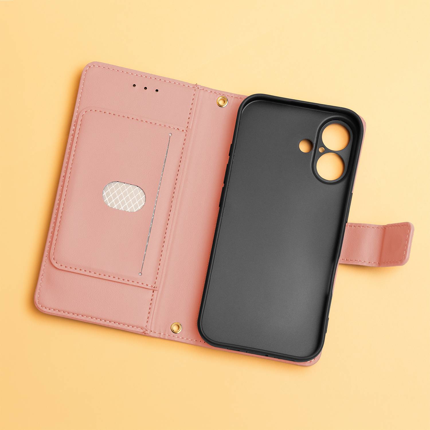 Ein schwarzes Smartphone-Case, das an einer rosa Schutzhülle im Portemonnaie-Stil auf hellgelbem Hintergrund befestigt ist, mit sichtbaren Kartensteckplätzen und einem Druckknopfverschluss.
