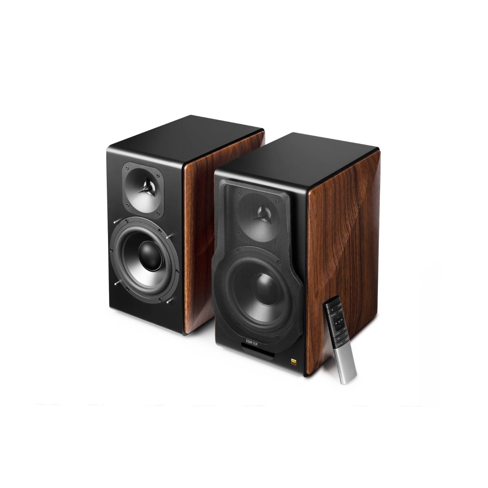 Zwei Holzlautsprecher mit schwarzen Frontseiten neben einer silbernen Fernbedienung, die ein modernes Audiosetup präsentieren.