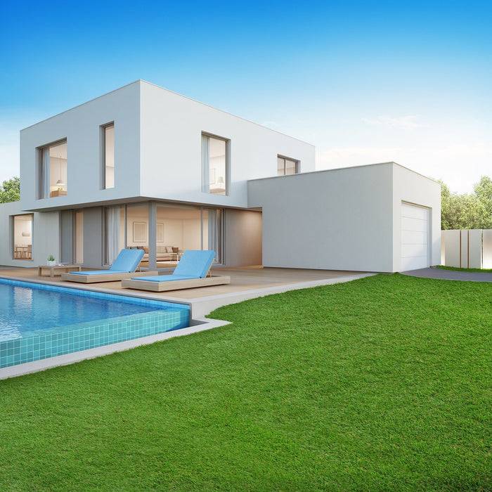 Modernes zweistöckiges weißes Haus mit großen Fenstern, einem Pool und einem geräumigen grünen Rasen unter einem klaren blauen Himmel.