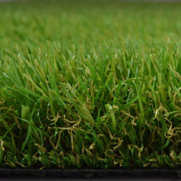 „Eine Nahaufnahme von der Seite eines Kunstrasenflecks, die dichte, realistische grüne Blätter mit einer schwarzen Basis darunter zeigt.