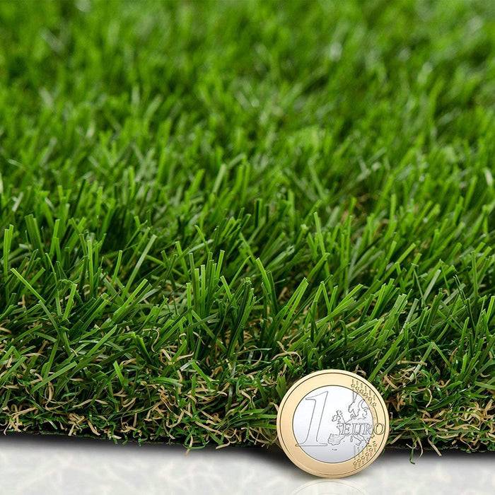 Eine Nahaufnahme von künstlichen Grashalmen mit einer Ein-Euro-Münze oben drauf, die die Rasentextur und die Münzengröße als Größenmaßstab zeigt.