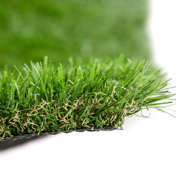 Nahaufnahme von Kunstrasen, die einen Querschnitt mit realistischen grünen Halmen und braunem Stroh zeigt.