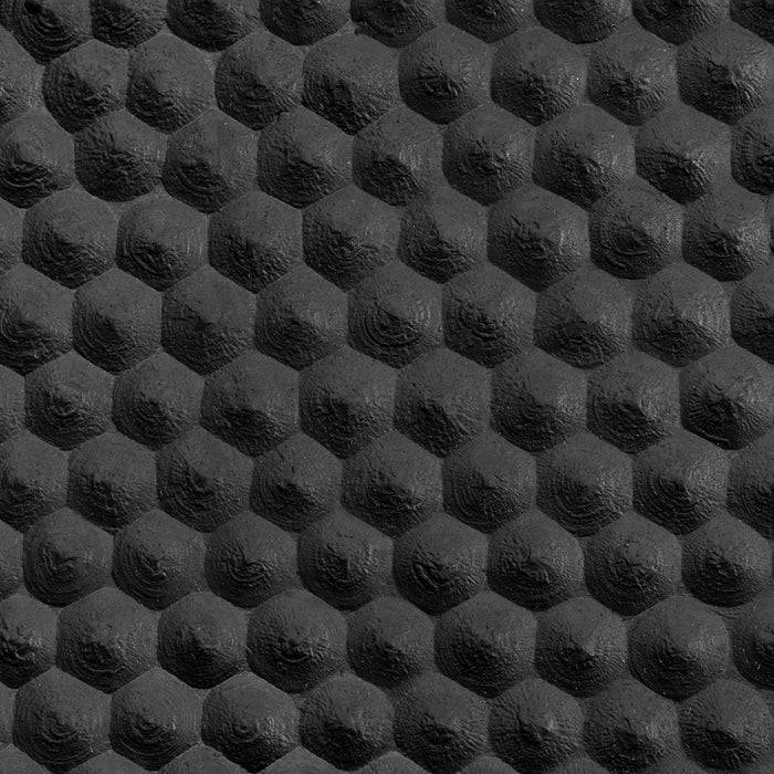 Nahaufnahme einer strukturierten schwarzen Oberfläche mit einem Wabenmustern, das durch Schatten und Lichter einen dreidimensionalen Effekt erzeugt.