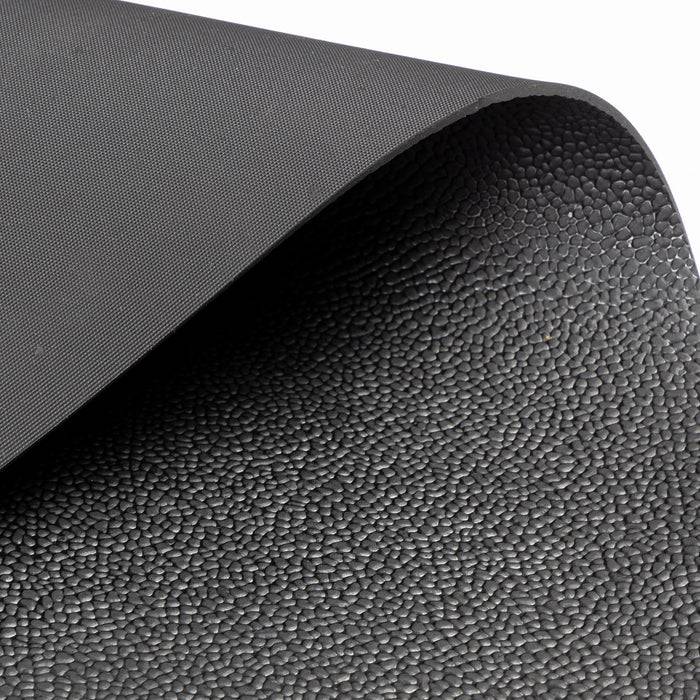 Eine strukturierte schwarze Yogamatte mit leicht aufgerollter Ecke, die ihre rutschfeste Oberfläche zur Schau stellt.