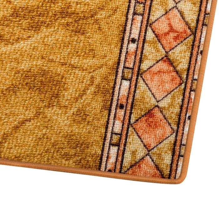 Eine Nahaufnahme einer goldbraun gefärbten Teppichecke mit einem geometrischen Randmuster, das Diamanten und Linien in Orange- und Beigetönen aufweist.