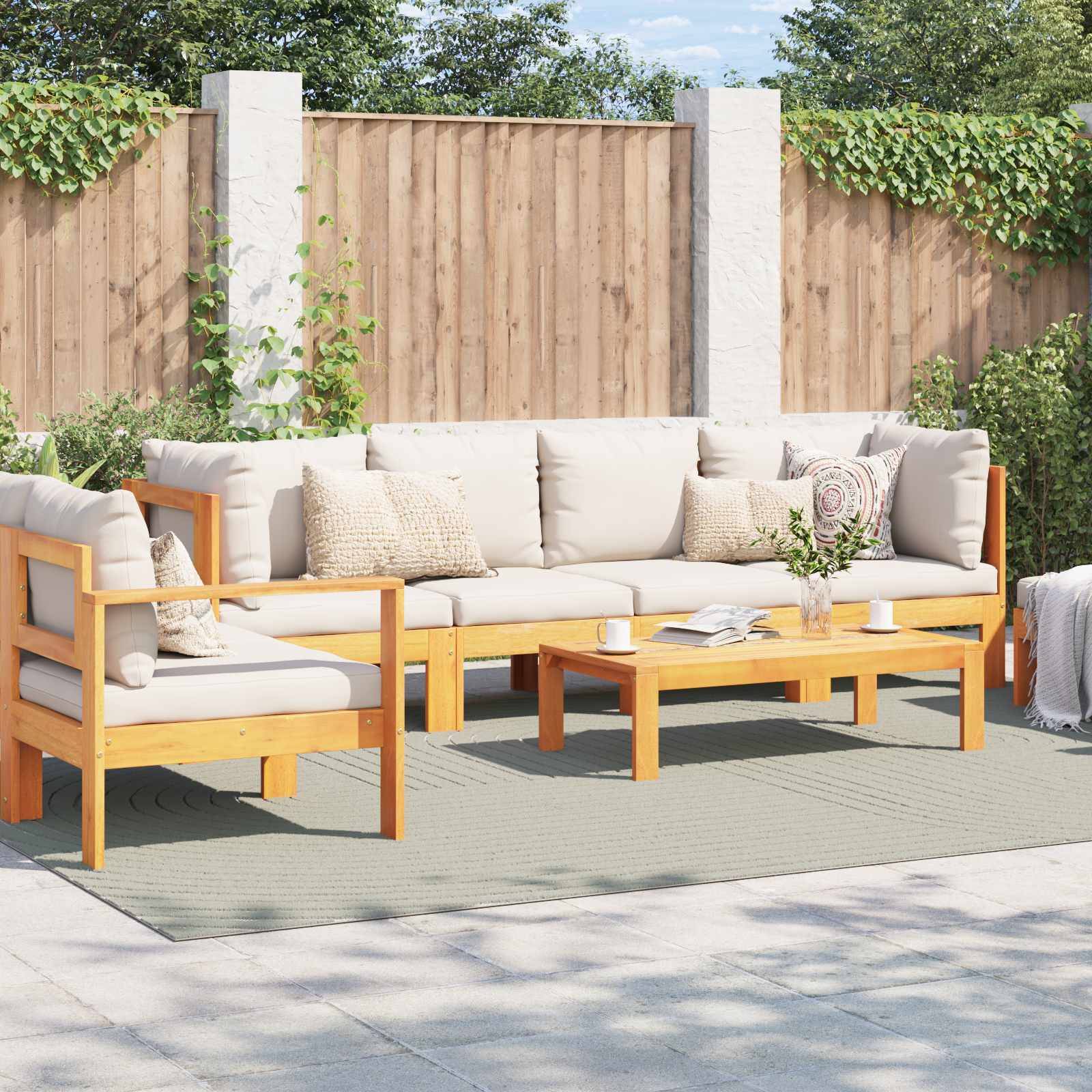 Ein Satz aus Holz-Gartenmöbeln mit beigen Kissen ist auf einer Terrasse aufgestellt. Ein Holz-Couchtisch und dekorative Kissen vervollständigen die gemütliche Anordnung.
