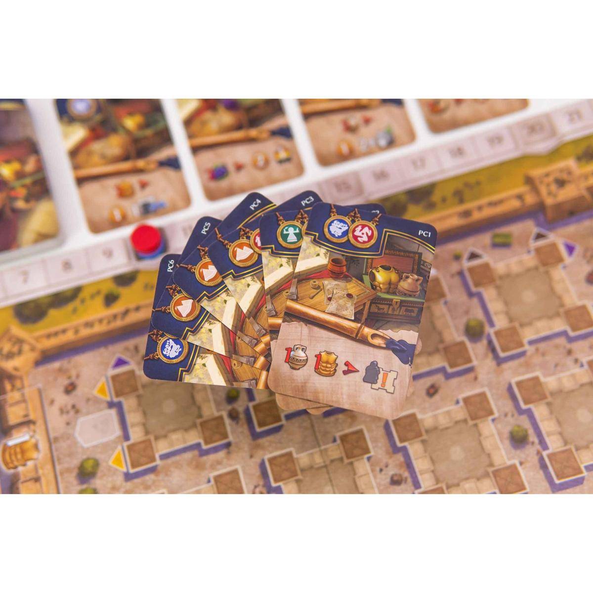 Spielkarten eines Brettspiels auf einem Spielbrett ausgelegt, die verschiedene Symbole und Gegenstände zeigen und auf strategische Spielelemente hindeuten.