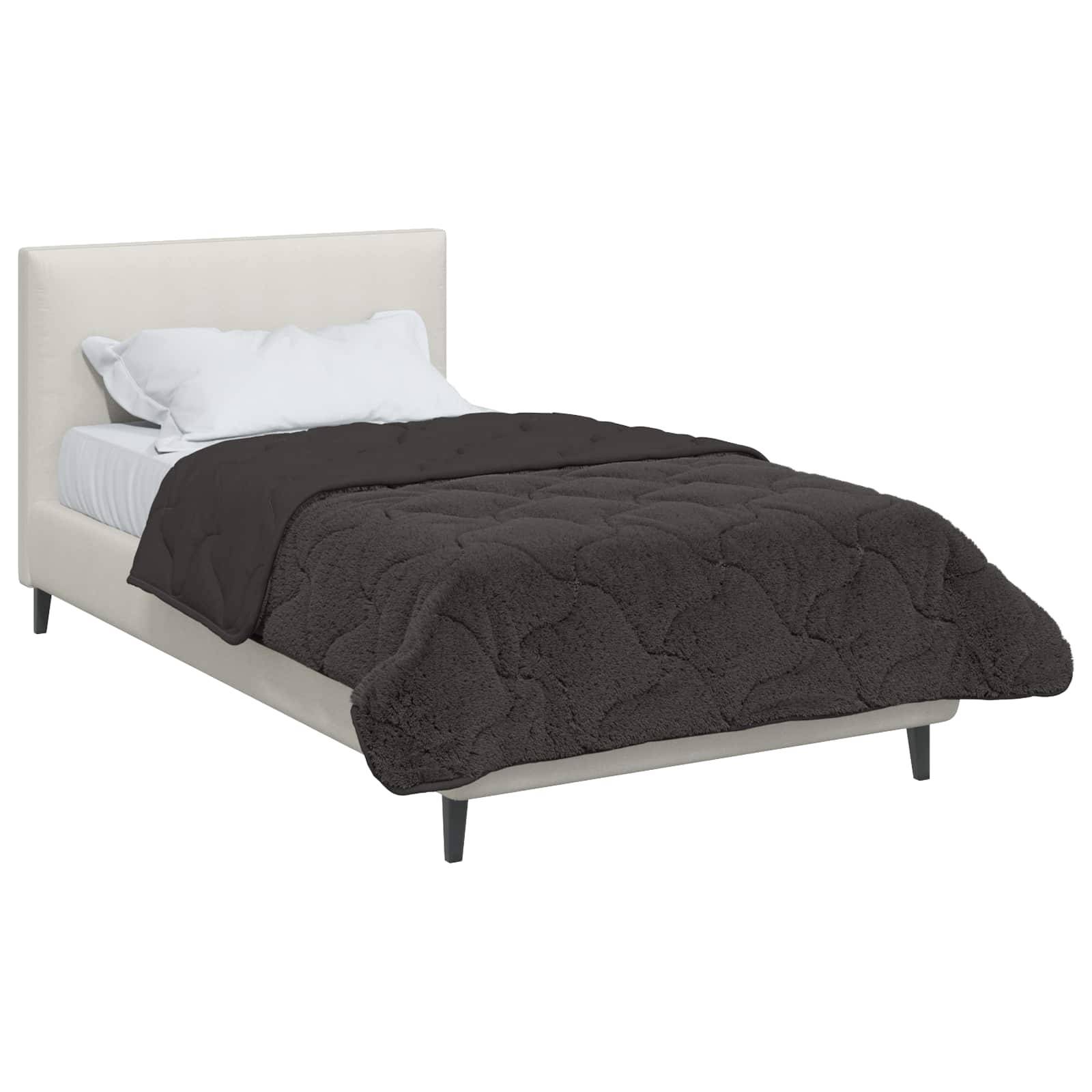 Ein weißes Bett mit einer schwarzen gesteppten Decke und weißen Kissen, aus einer Seitenansicht gezeigt, die das einfache, moderne Design präsentiert.