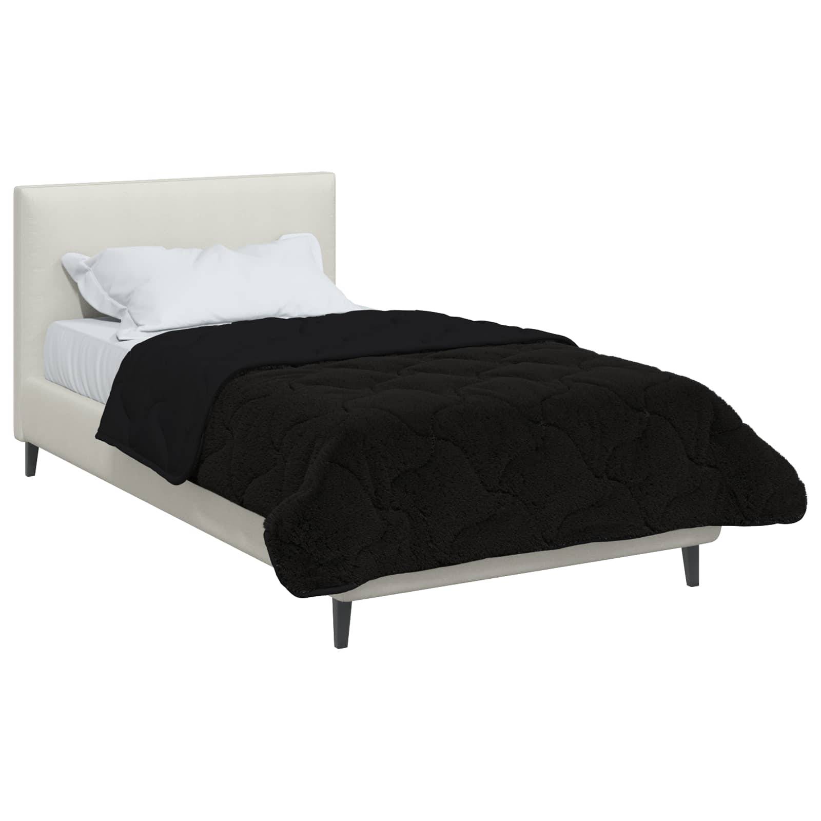 Ein modernes weißes Bett mit einer schwarzen gesteppten Decke und weißen Kissen.