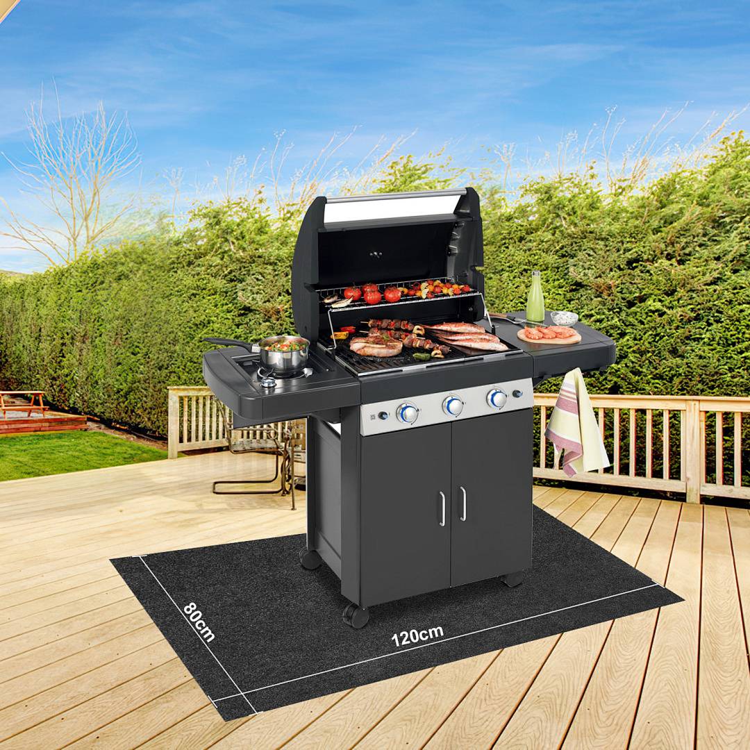 Ein Edelstahl-Außengrill auf einer Terrasse mit geöffnetem Deckel, auf dem Fleisch und Gemüse garen. Umgeben von Grünflächen, klarer Himmel oben.