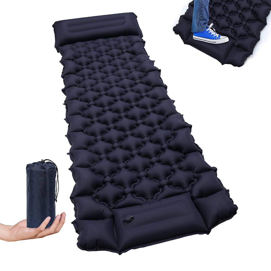 Kompaktes aufblasbares Schlafpad, schwarz, mit Kissensektion und Transporttasche. Ideal zum Campen. Der blaue Schuh einer Person ist teilweise sichtbar.